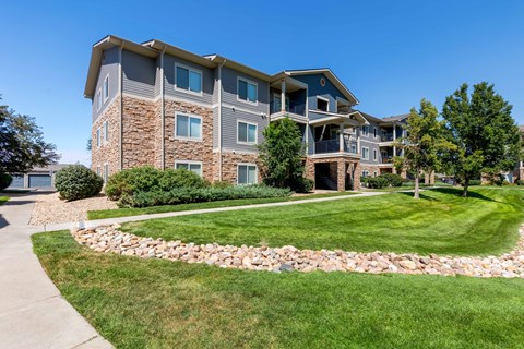 an apartment building with grass and trees in front of it