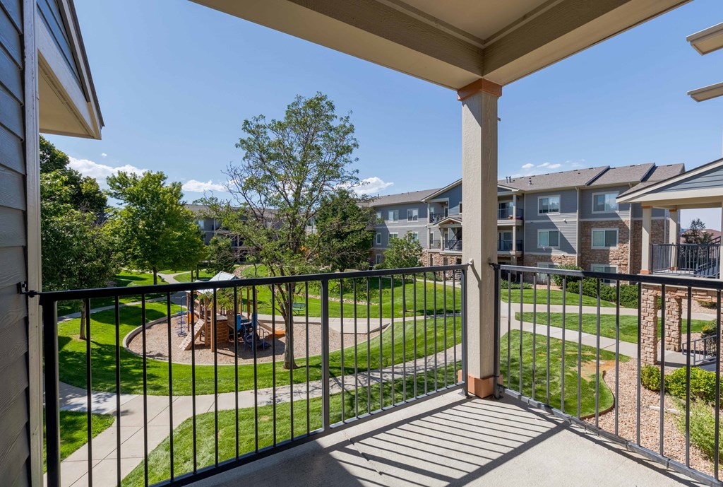 a balcony with a view of a yard and apartment buildings