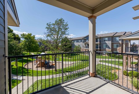 a balcony with a view of a yard and apartment buildings