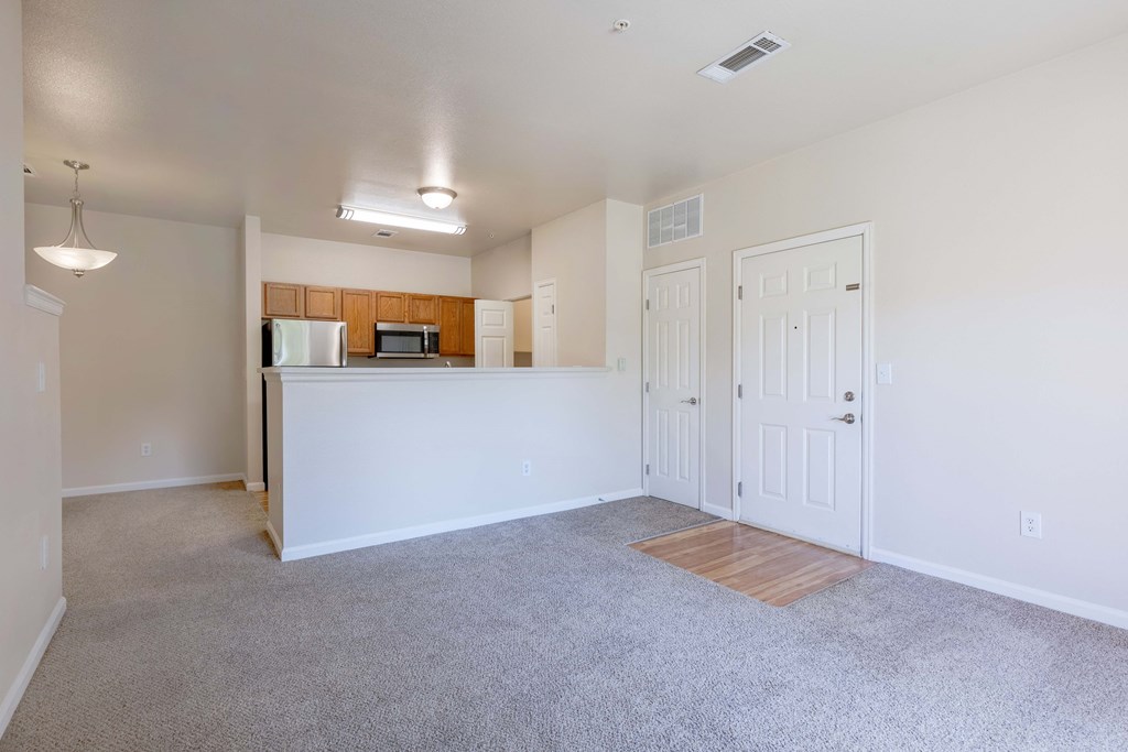 an empty living room and kitchen with white walls and carpeting