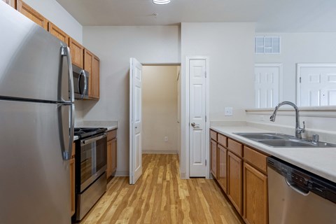 an empty kitchen with stainless steel appliances and wood flooring