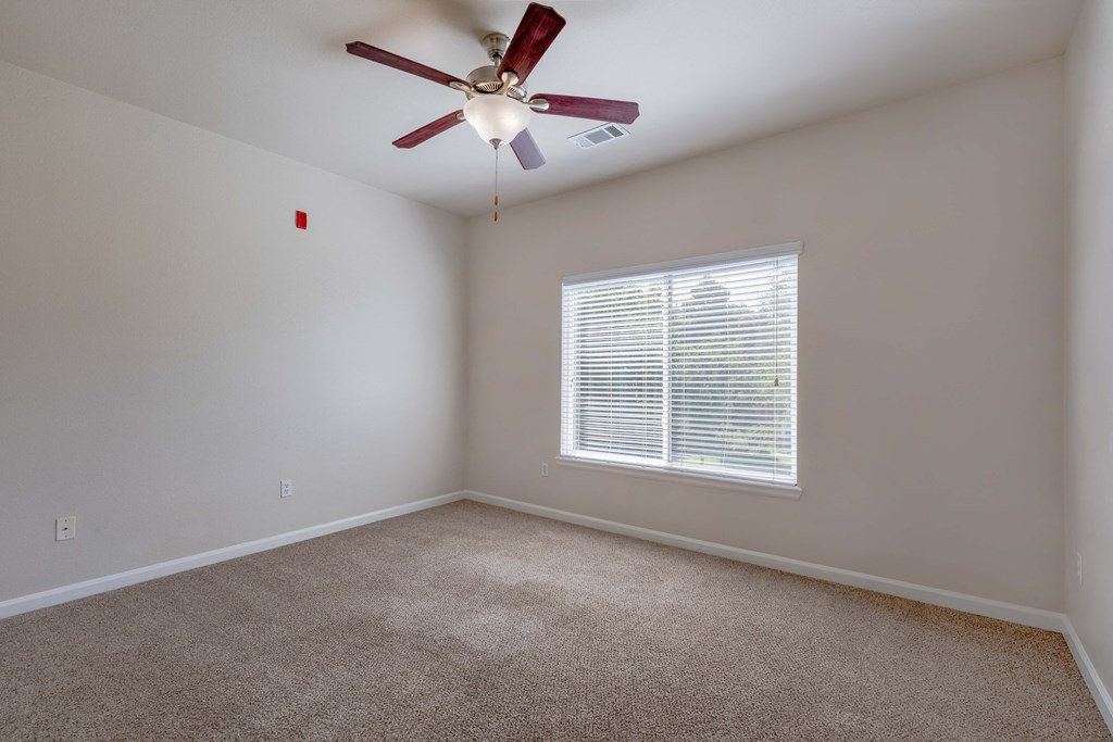 an empty room with a ceiling fan and a window