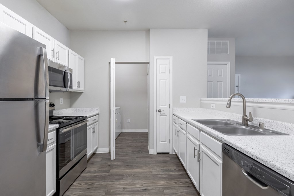 an empty kitchen with white cabinets and stainless steel appliances