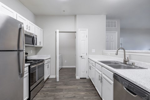 an empty kitchen with white cabinets and stainless steel appliances