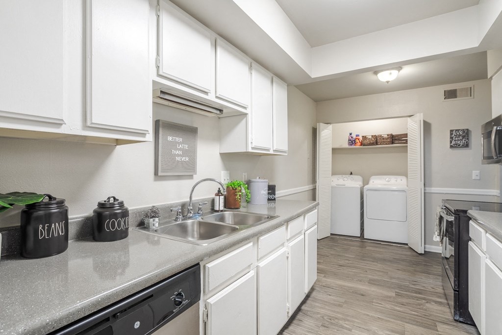 a spacious kitchen with white cabinets and a stainless steel counter top and a laundry room
