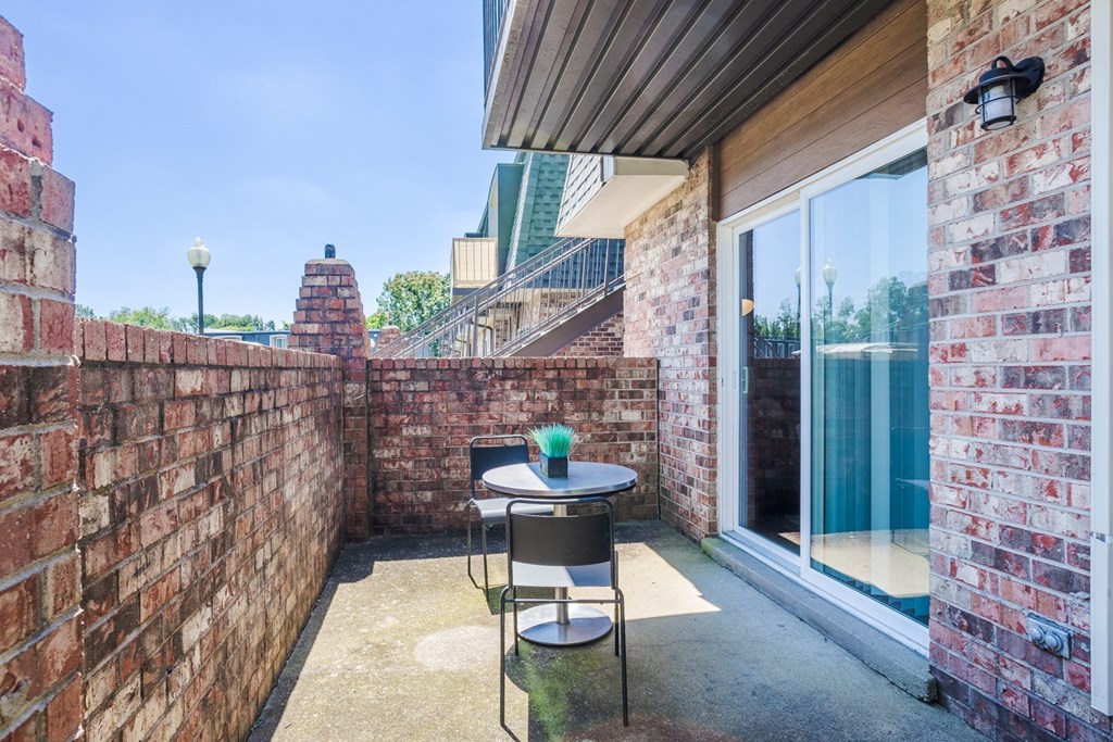 a balcony with a table and a chair and a brick wall