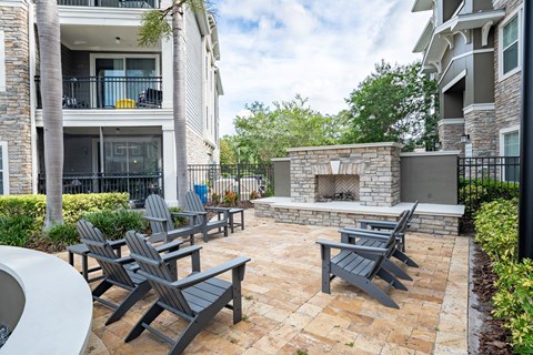 A patio with a fireplace and chairs.