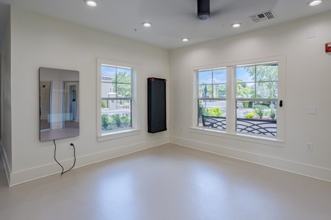 A spacious room with a black speaker and a large window overlooking a parking lot.