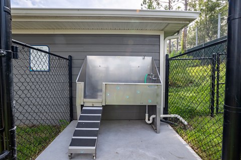 A metal structure with a ramp leading to a door is surrounded by a black fence.