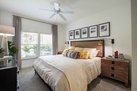 A bedroom with a large bed, a ceiling fan, and a window with curtains.