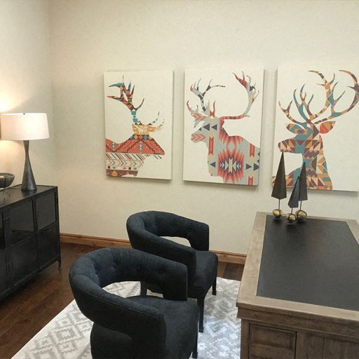a living room with two chairs and paintings of deer