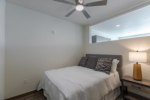 A bedroom with a bed, nightstand, and a ceiling fan.