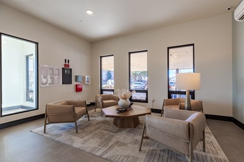 A living room with a grey carpet and beige chairs.