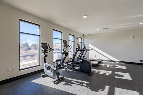 A spacious gym with treadmills, elliptical machines, and a large window.