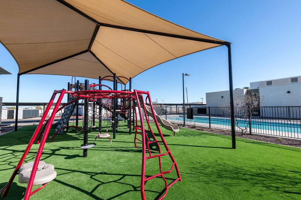 a playground with a swing set and a pool in the background