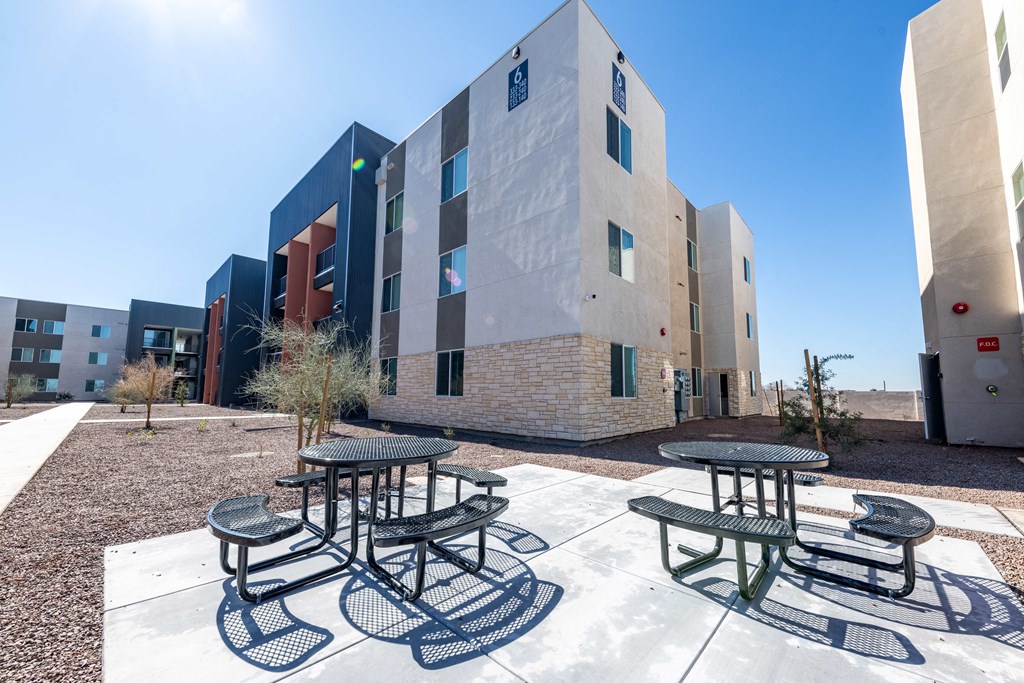 a patio with two tables and chairs in front of a building