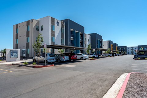 A parking lot in front of a modern building with cars parked.