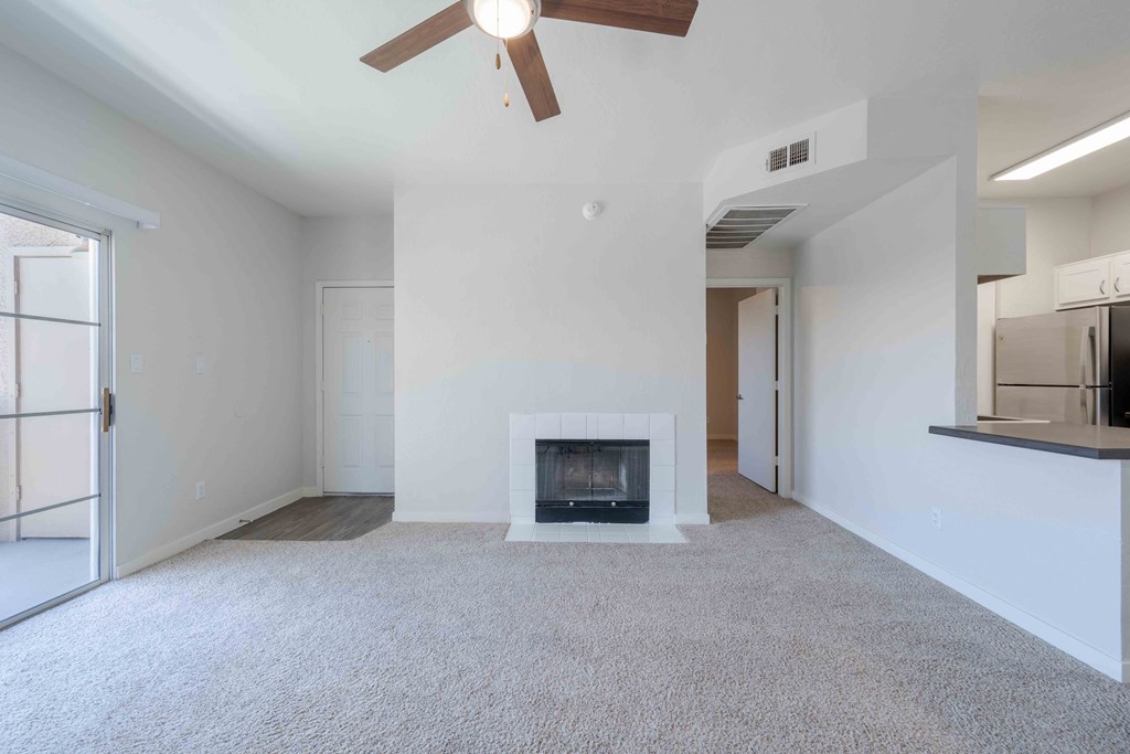 A living room with a fireplace and a ceiling fan.