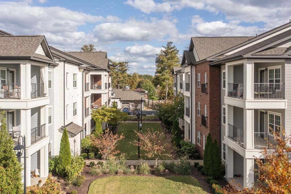 an aerial view of a grassy area between several apartment buildings