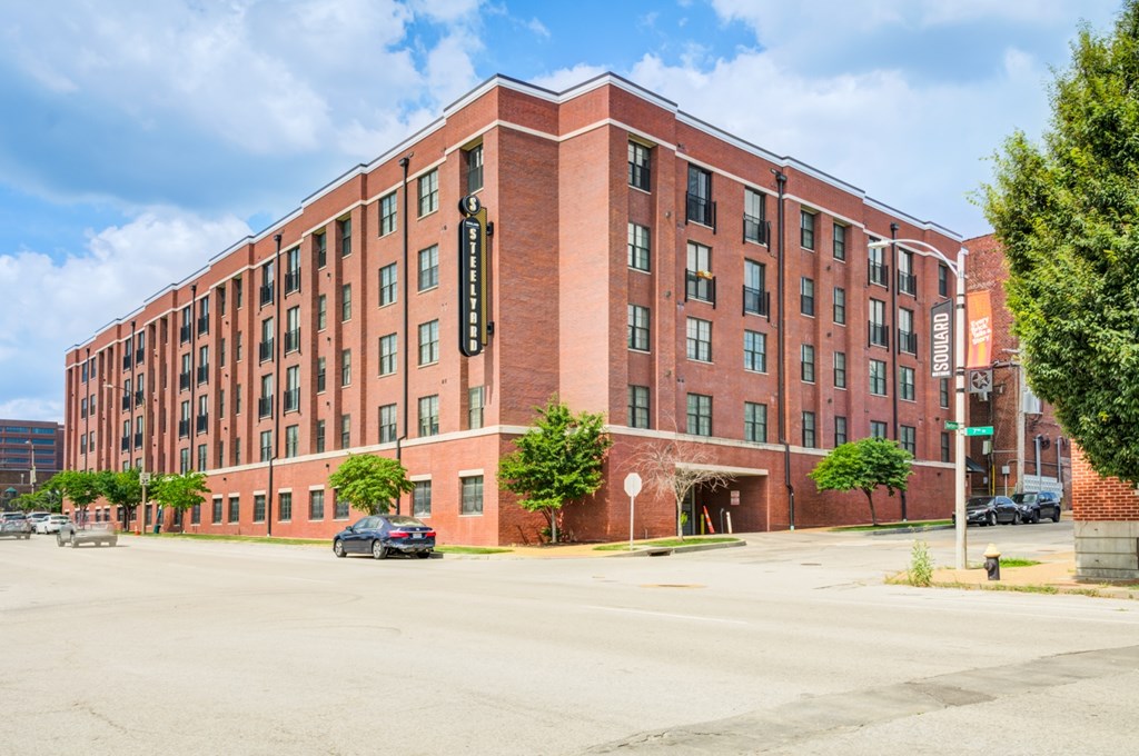 A red brick building with a parking lot in front.