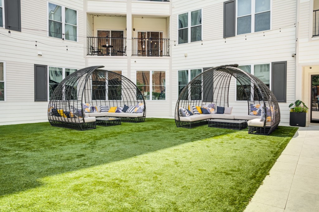 Two black and yellow outdoor chairs are placed on a green lawn.