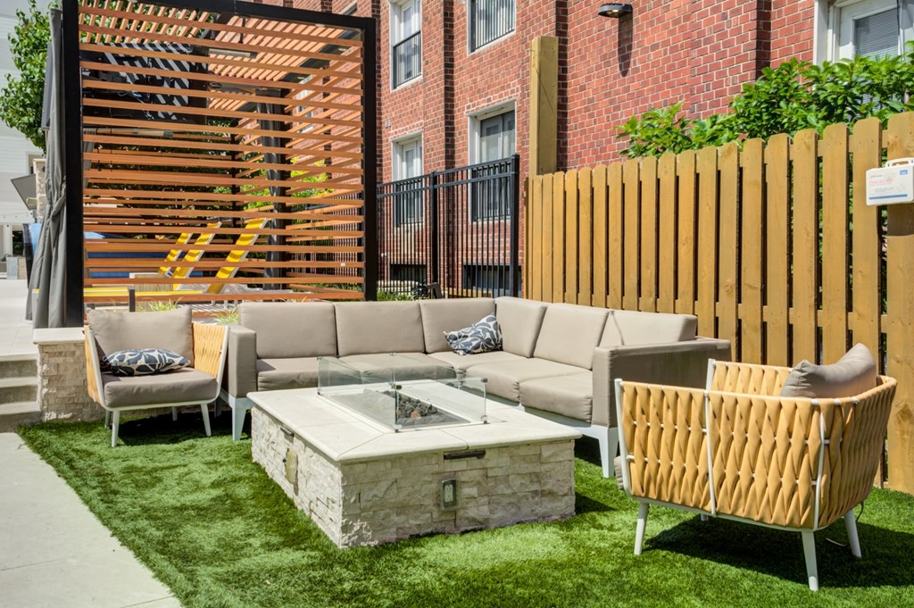 A patio with a couch, chairs, and a table with a stone base.