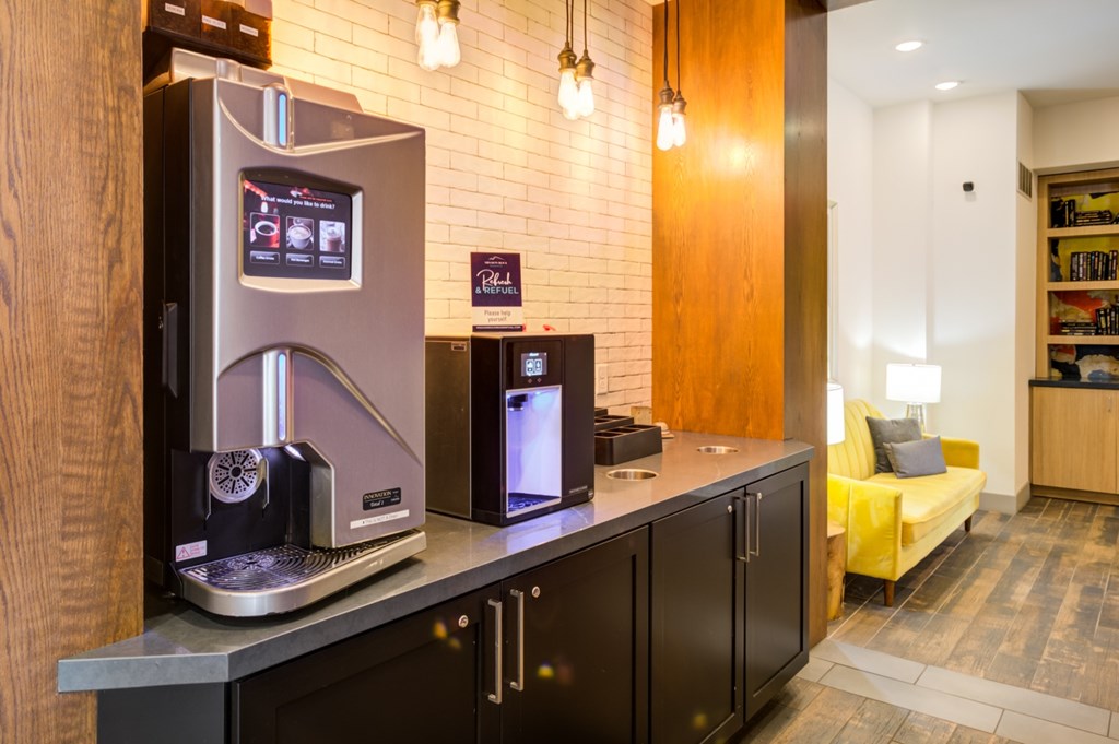 A modern coffee machine is on a counter in a well-lit room.