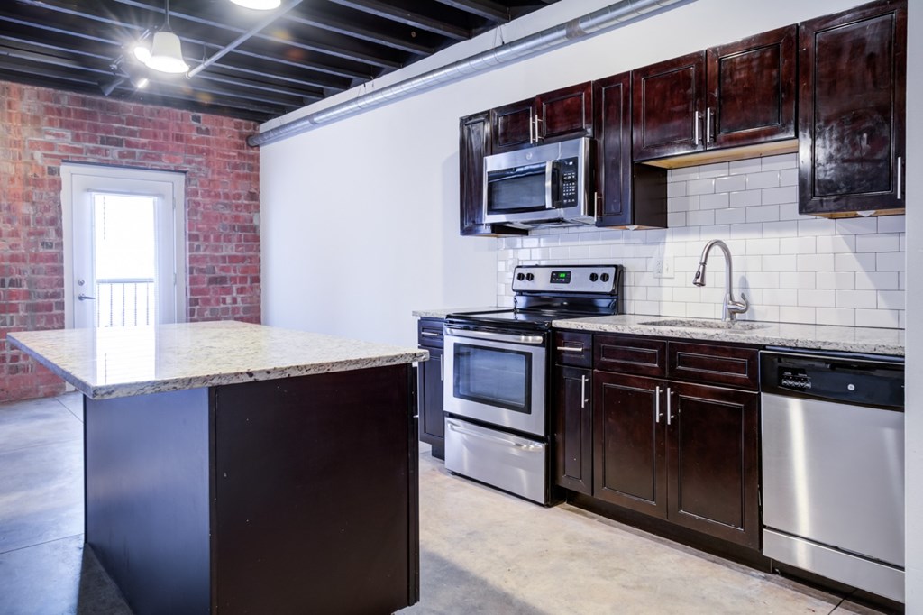 A kitchen with a brick wall and stainless steel appliances.