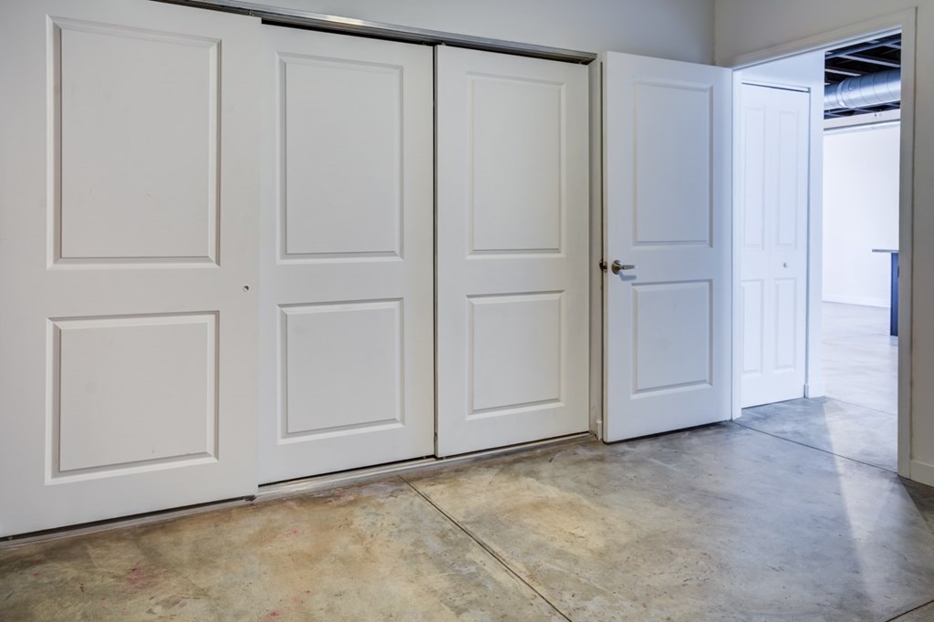 A room with four white doors and a concrete floor.
