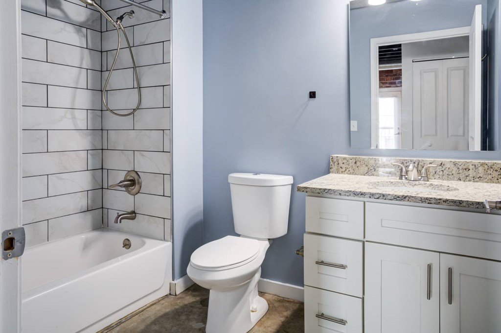 A white toilet sits next to a white bathtub in a bathroom.