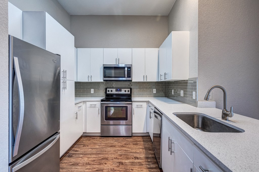 an empty kitchen with white cabinets and stainless steel appliances