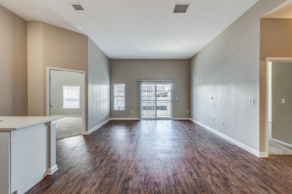 the living room and dining room of an empty house with wood flooring