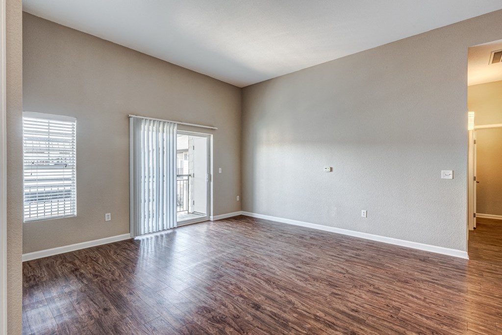 an empty living room with wood flooring and a sliding glass door