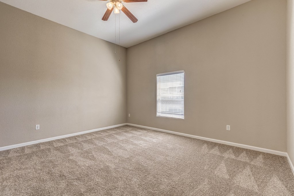 an empty living room with carpet and a ceiling fan