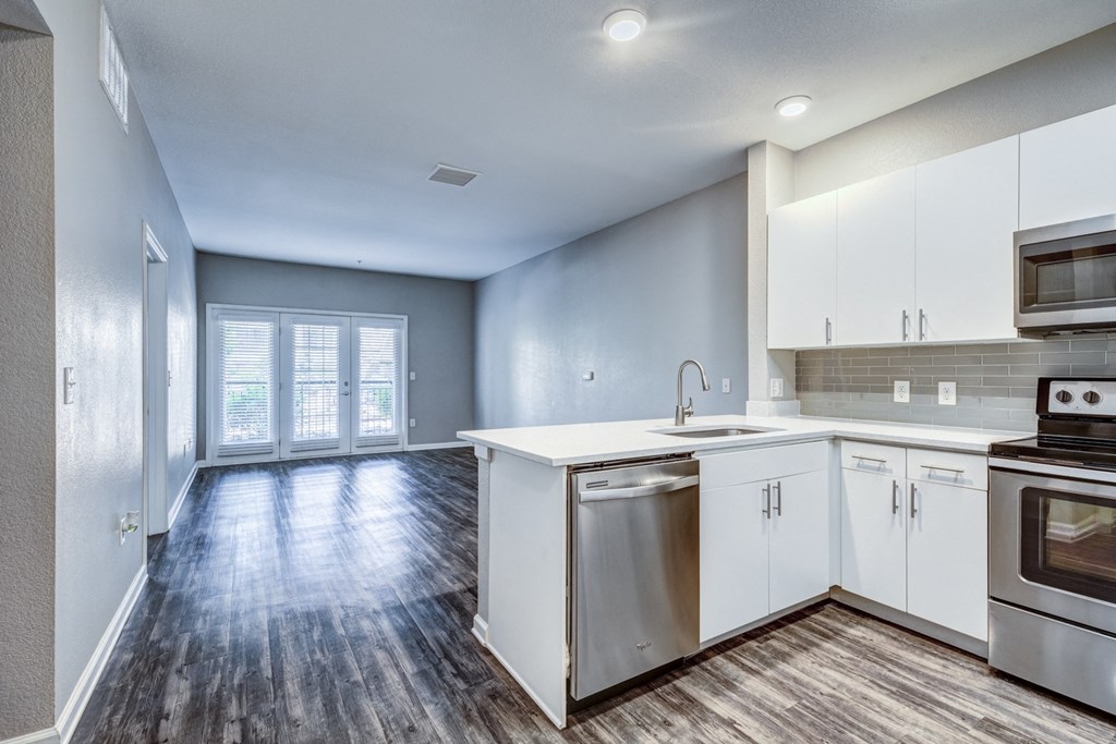 an empty kitchen with white cabinets and stainless steel appliances