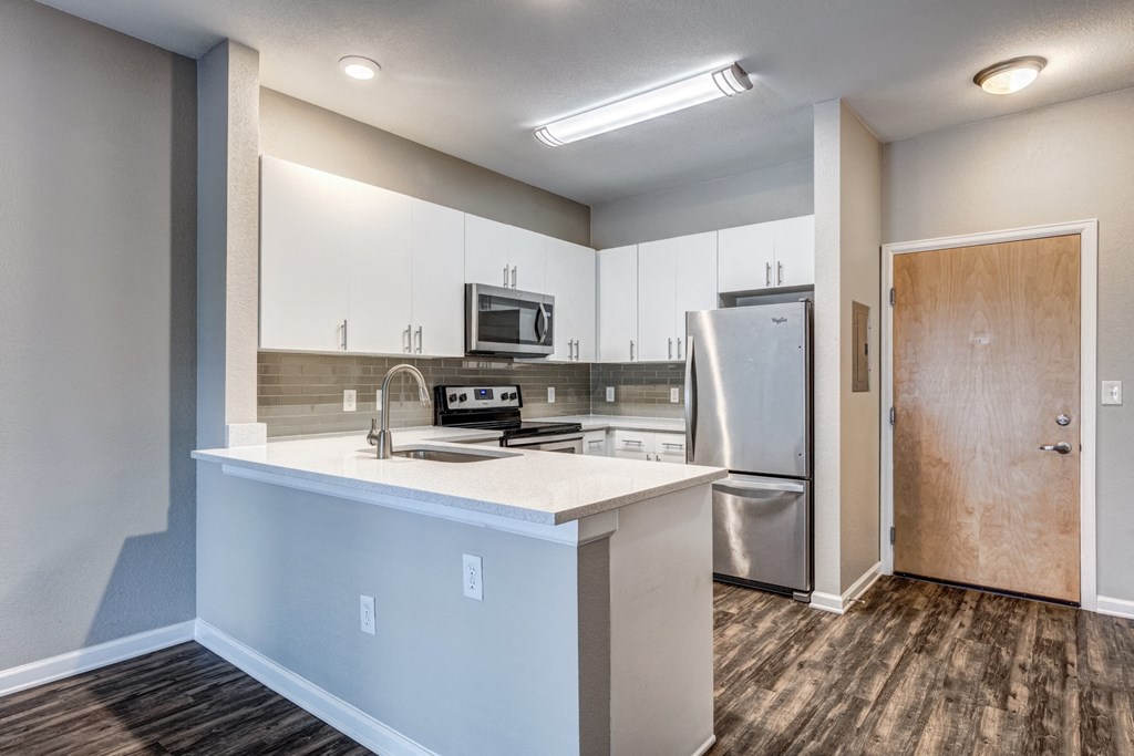 an empty kitchen with white cabinets and a stainless steel refrigerator