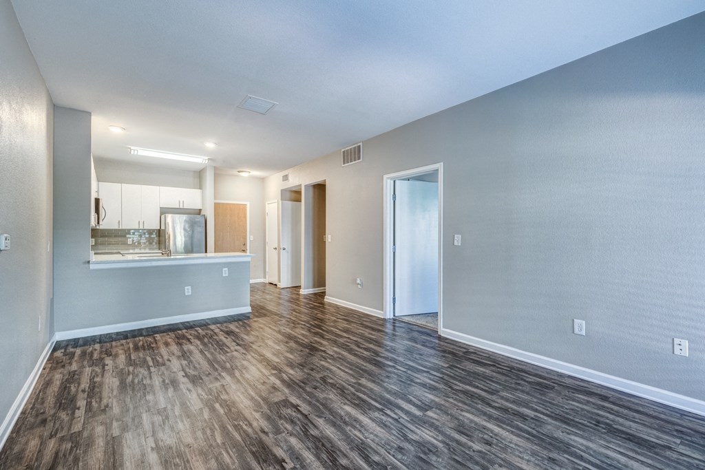 the living room and kitchen of an apartment with wood flooring