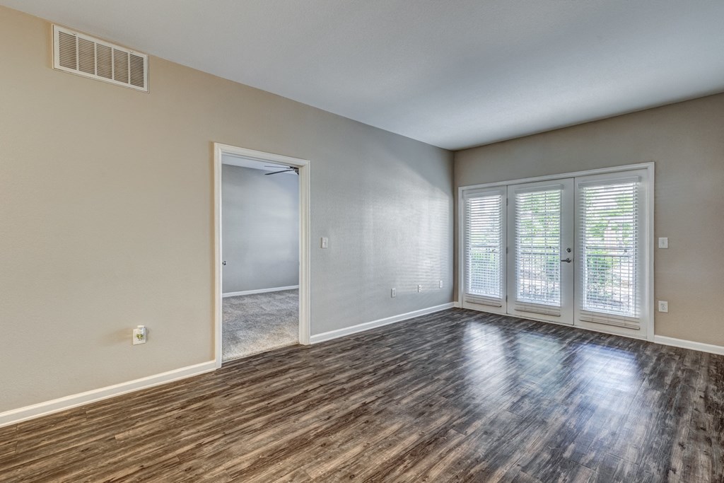 an empty living room with wood flooring and a door to a hallway