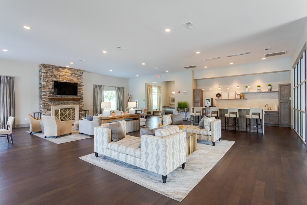 Community clubhouse with couches, chairs, and stone fireplace with tv