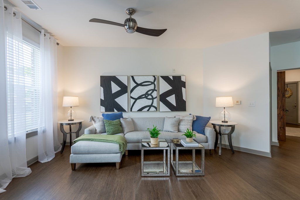 A living room with a grey couch, a coffee table, and a ceiling fan.