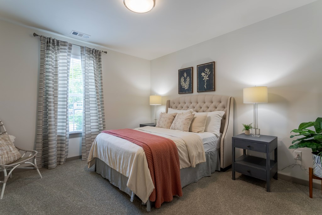 A bedroom with a large bed and a chair.