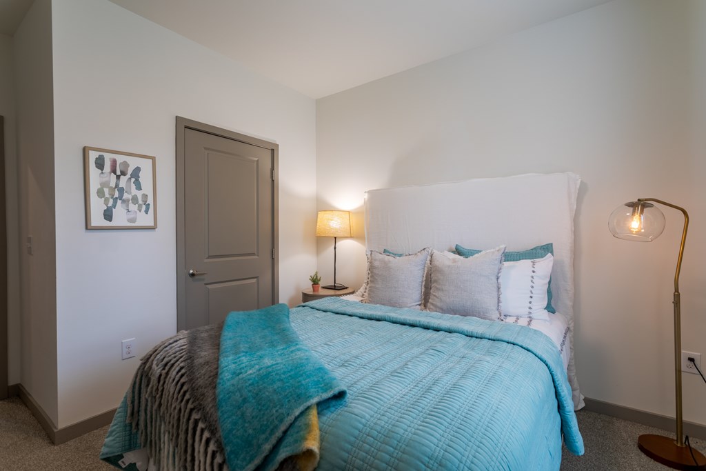 A bedroom with a bed covered in a blue blanket.