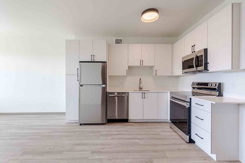 A kitchen with white cabinets and a stainless steel refrigerator.