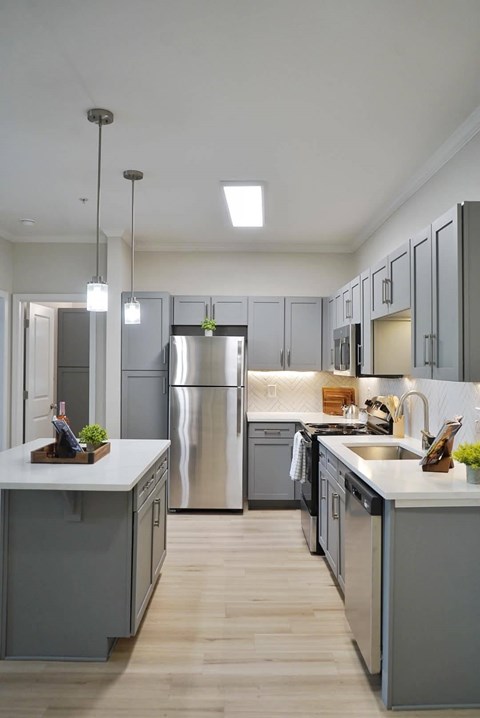 A modern kitchen with a white countertop and stainless steel appliances.