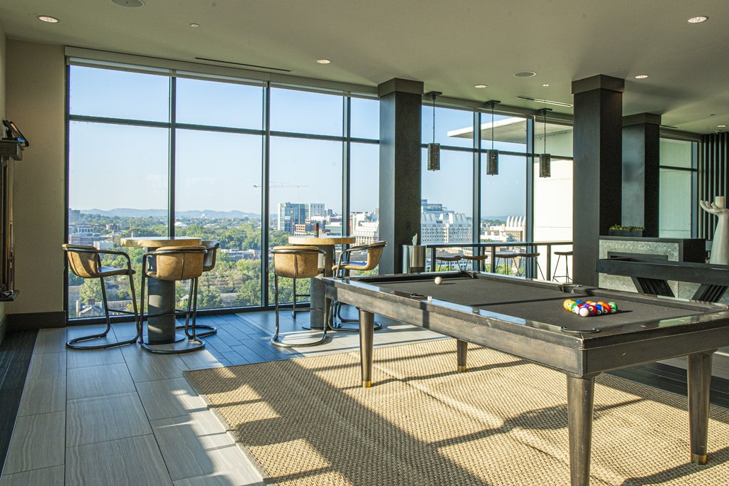A pool table in a room with a view of the city.