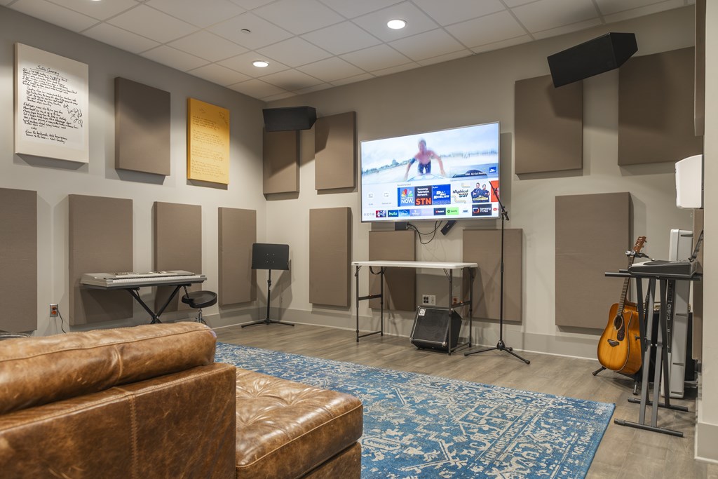 A room with a couch, a guitar, and a television screen showing a person on a treadmill.