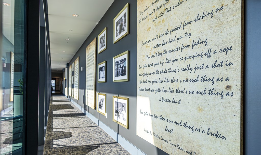 A hallway with a wall of framed pictures and a wall of text.
