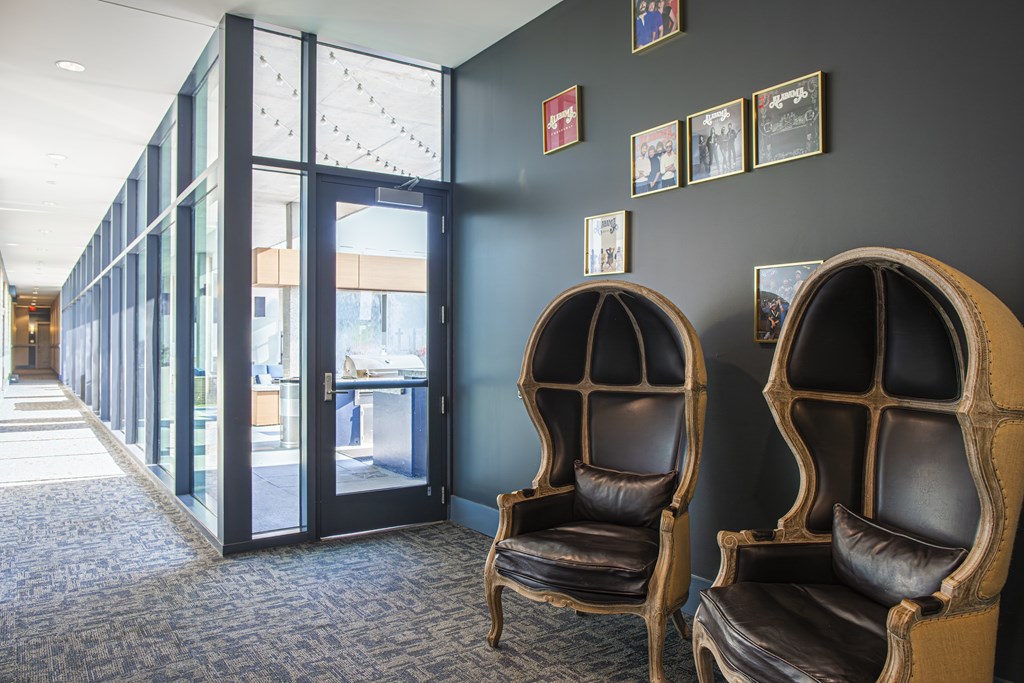 Two leather chairs are placed in front of a wall with pictures.