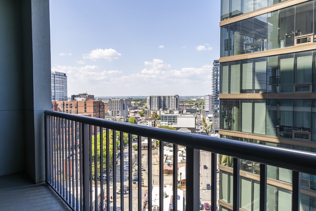 A balcony overlooks a cityscape with buildings and cars.