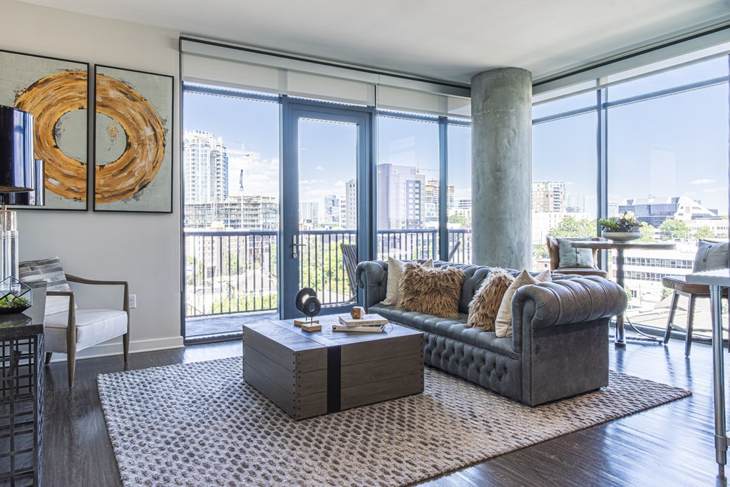 A living room with a large window and a view of the city.